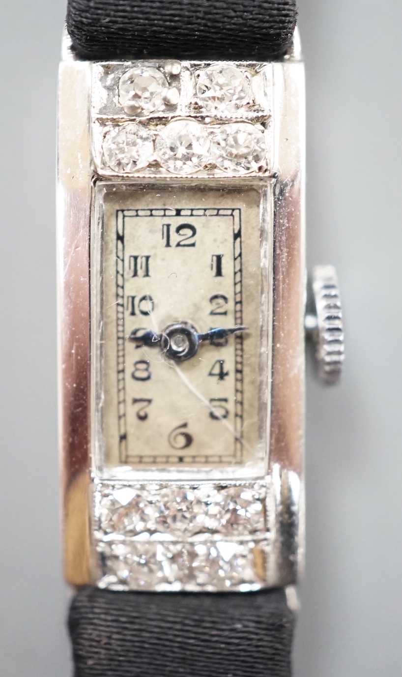 A lady's white meat (stamped Platinum) and diamond set rectangular manual wind cocktail watch, case diameter 11mm, on a black fabric strap, gross weight 10.3 grams.